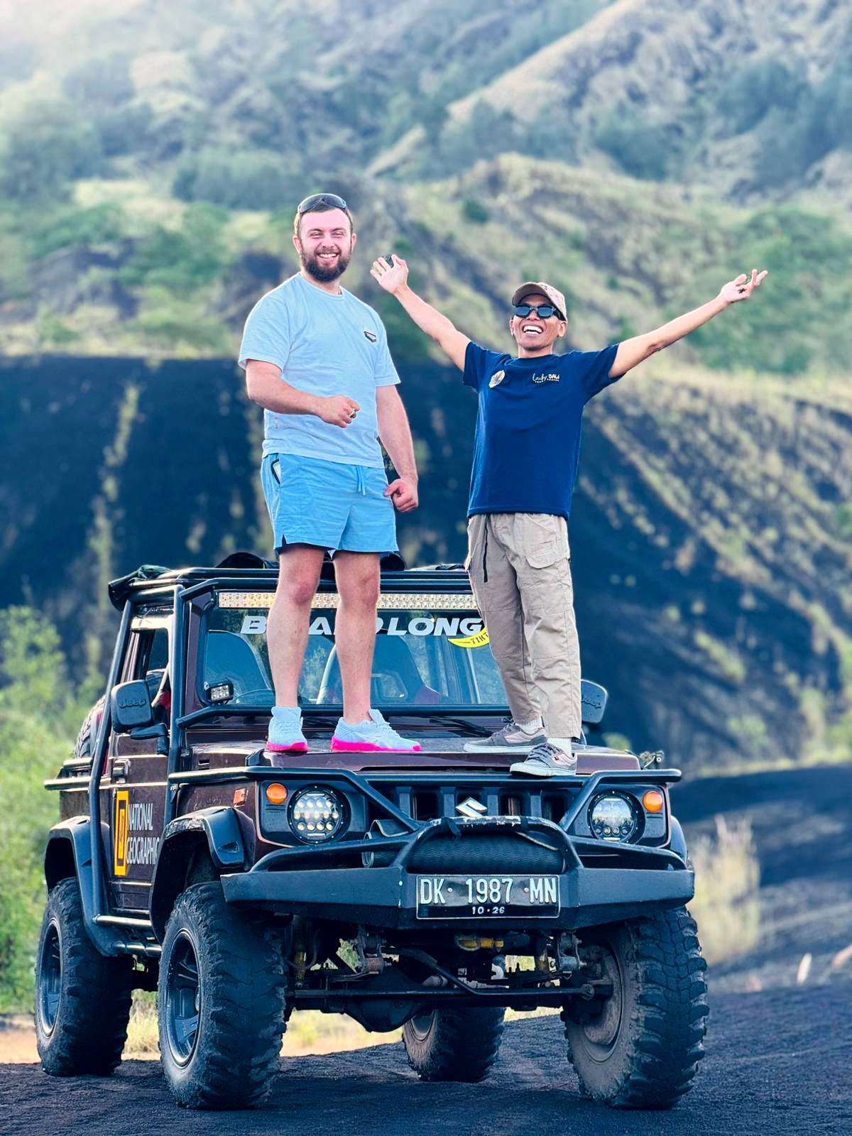 Guest and guide standing on a 4WD jeep on the Mount Batur black lava