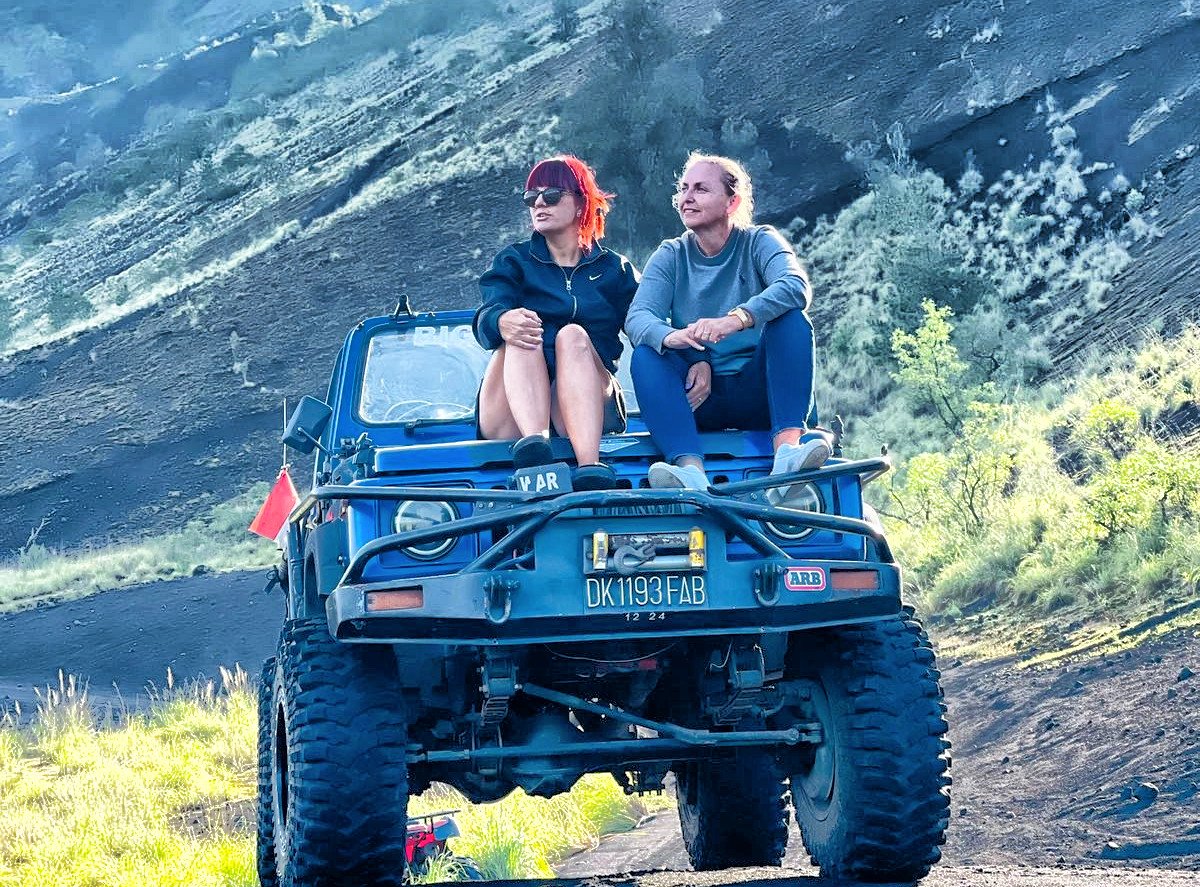 Two guests sitting on a blue 4WD jeep on the Mount Batur lava field